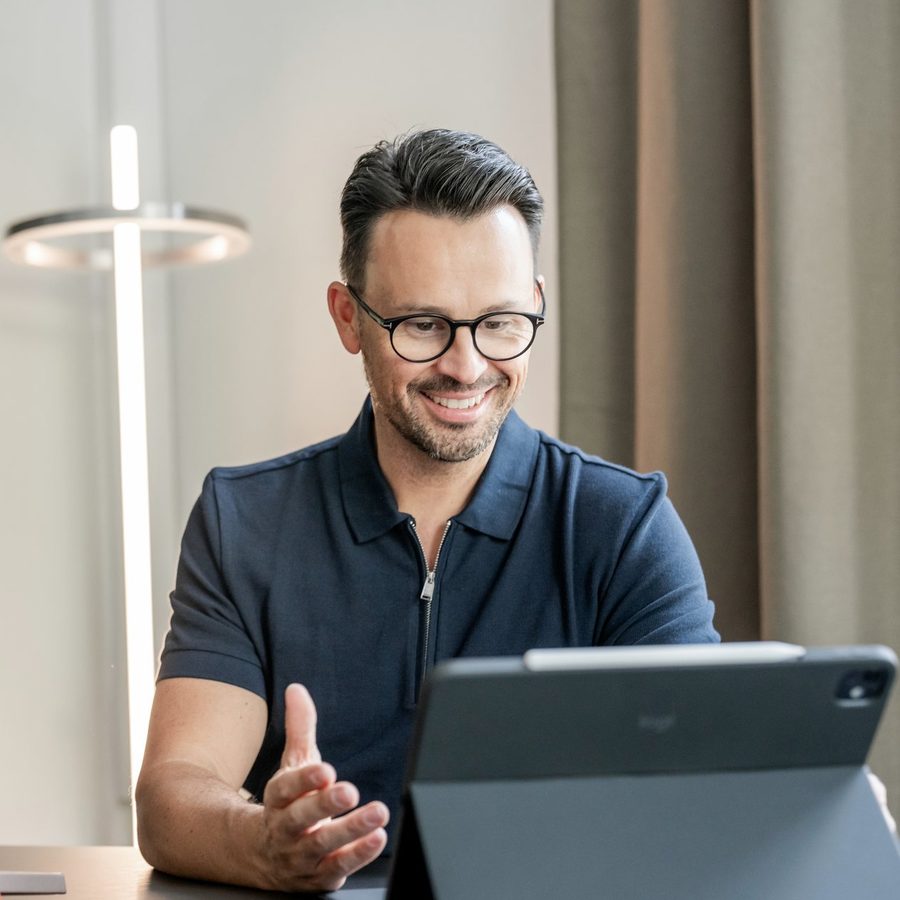 Manfred Braun im Polo am Tisch, lächelt und antwortet am Tablet